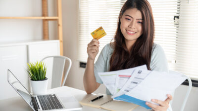 Mulher com contas e cartão na mão parcelando boleto