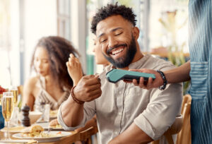 Homem sorrindo ao passar cartão em maquininha