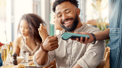 Homem sorrindo ao passar cartão em maquininha