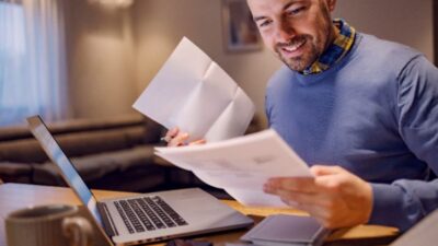 Mãos segurando um smartphone mostrando aplicativo de controle financeiro com tela de parcelamento de boletos