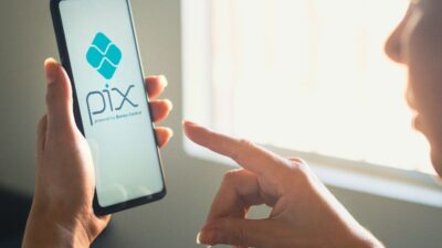 Celular mostrando aplicativo financeiro com código QR Pix e cartão de crédito ao lado