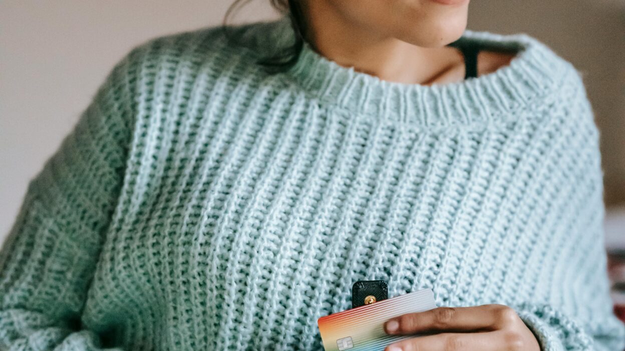 Young black businessman using credit card and smart phone while shopping online in the office