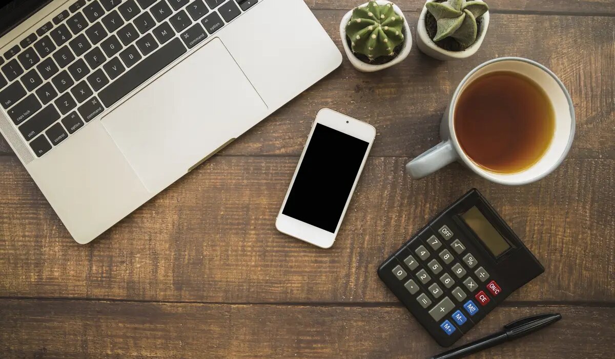 Workspace with laptop and smartphone near tea cup